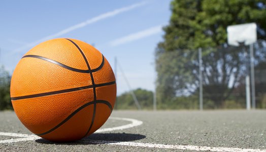 A basketball on asphalt with a hoop in the background